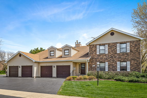 Front view of a two-story house with a three-car garage and brick facade.