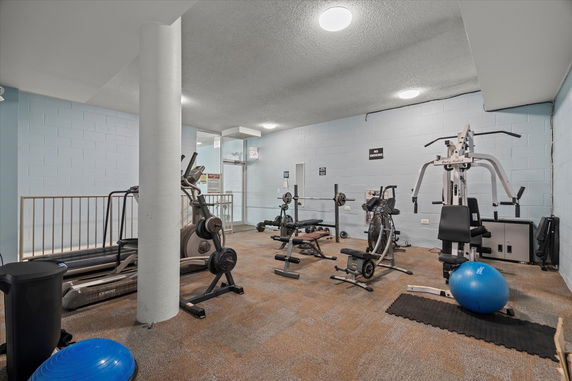 Indoor gym area with exercise equipment including treadmills, weight benches, and exercise bikes.