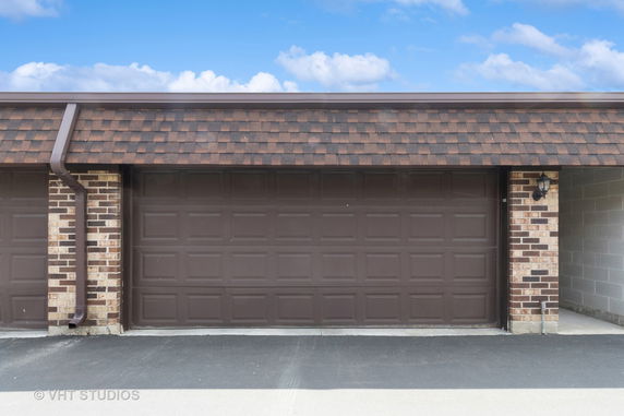 Front view of a garage with a brown angled roof and brick siding.