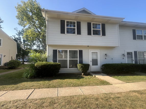Front view of a two-story house with white siding and black shutters.