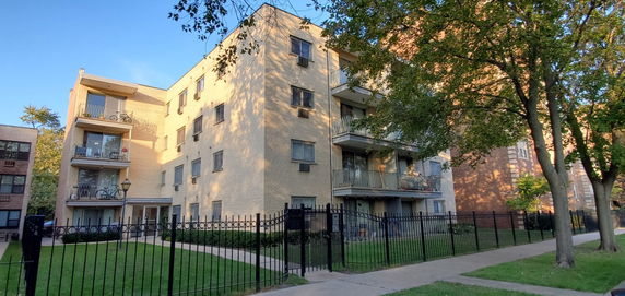 Front view of a multi-story apartment building with balconies and brick exterior.