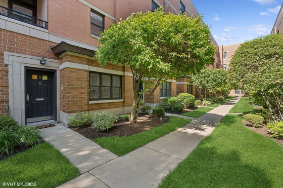 Front view of a brick apartment building with a small pathway and landscaped garden.