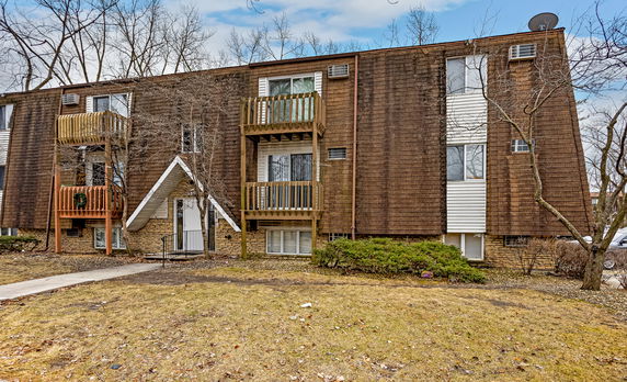 Front view of a multi-story building with wood siding and small balconies.