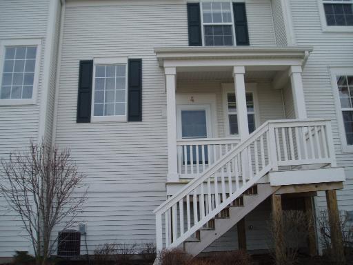 Front view of a house with a small porch and stairs leading to the entrance.