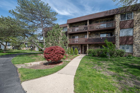 Front view of a multi-story apartment building with balconies and a pathway leading to the entrance.