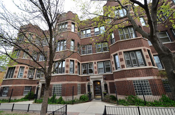 Front view of a multi-story brick apartment building with multiple windows.
