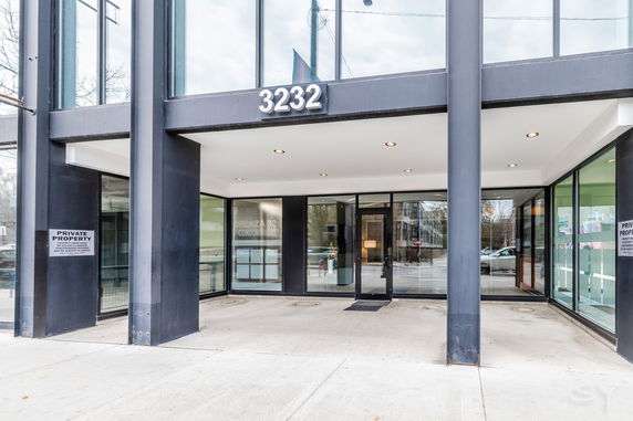 Front view of a modern building entrance with large glass windows and a canopy.