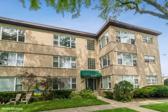 Front view of a three-story apartment building with a green awning over the entrance.