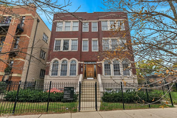Front view of a multi-story brick building with large windows and a central staircase.