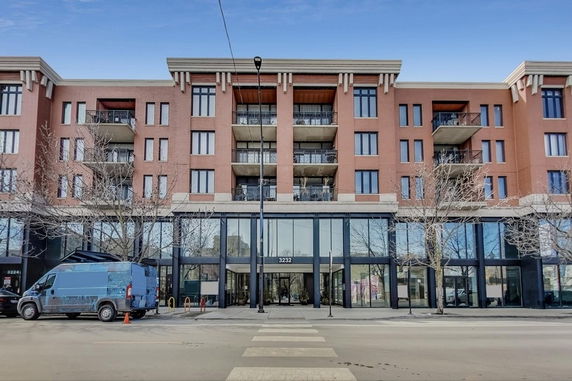 Front view of a multi-story building with balconies and a glass entrance.