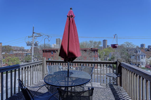 Panoramic view from a terrace with outdoor furniture and city skyline in the background.