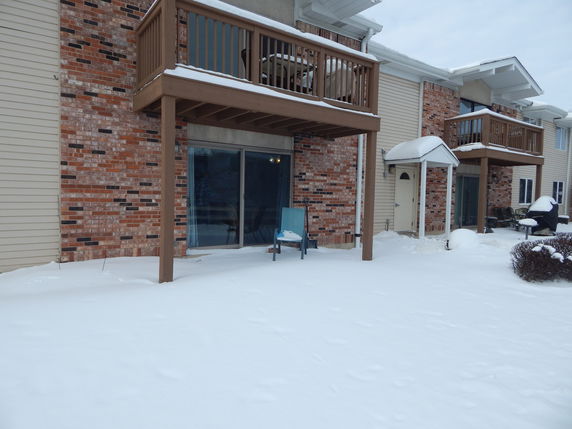 Front view of a multi-unit building with balconies and snow covering the ground.