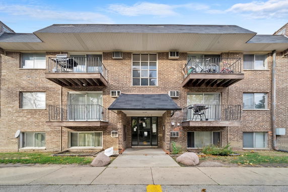 Front view of a multi-story brick apartment building with balconies.