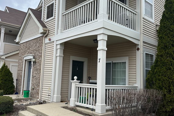 Front view of a two-story house with a balcony and brick accents.