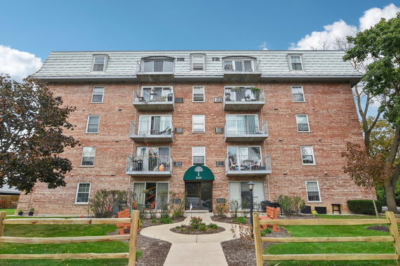 Front view of a multi-story brick apartment building with balconies.