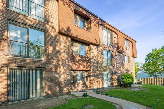 Front view of a multi-story brick building with large windows and balconies.