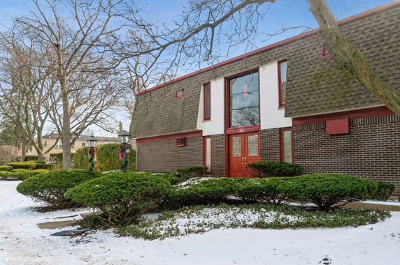Front view of a two-story building with brick exterior and red doors.