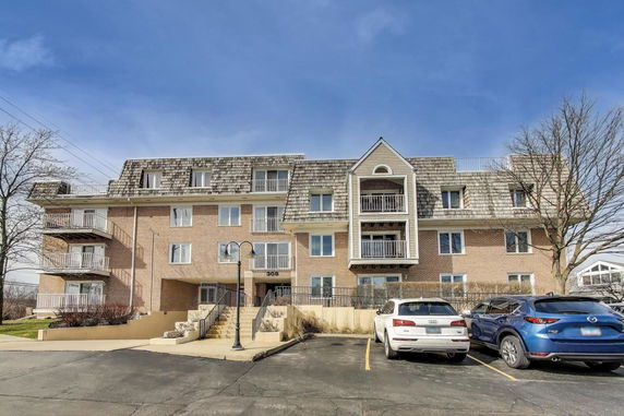 Front view of a multi-story brick building with balconies and a gabled roof.