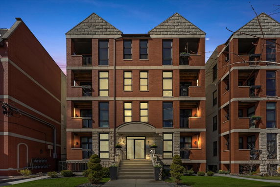 Front view of a multi-story brick apartment building with multiple balconies.