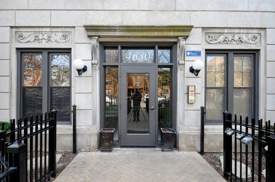 Front view of a building entrance with decorative details and double windows on either side of the door.