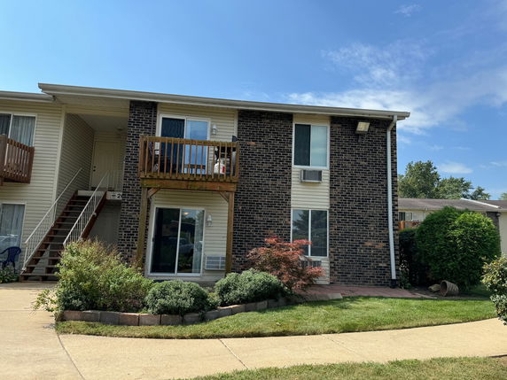 Front view of a two-story building with a balcony and brick exterior.