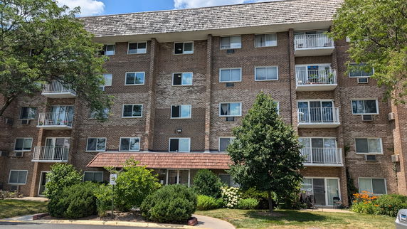 Front view of a multi-story brick apartment building with balconies.