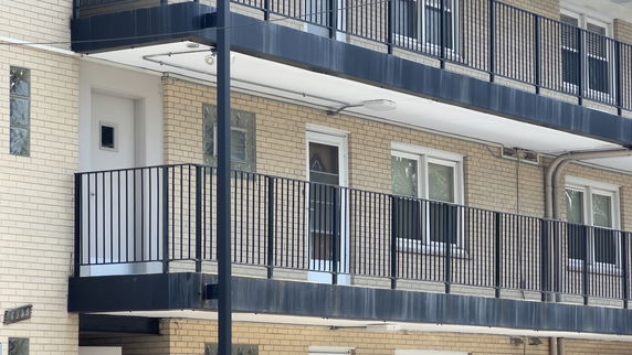 Front view of a multi-story building with balconies and brick exterior.