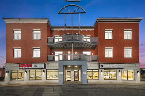 Front view of a multi-story commercial building with a brick facade and balconies.