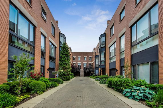 Front view of modern brick townhouses with glass windows and landscaped walkway.