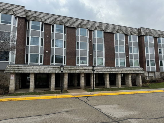 Front view of a three-story building with bay windows and stone pillars.