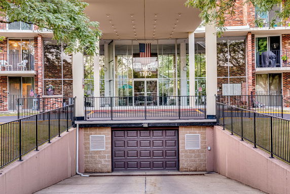 Front view of a multi-story building with a glass entrance and a parking garage below.