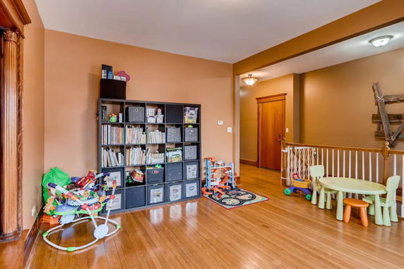 Room with a bookshelf and children's play area, featuring toys and a small table with chairs.