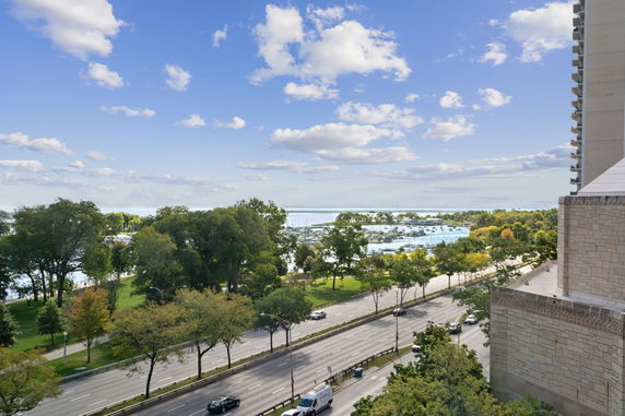 Panoramic view of a scenic area with a road, trees, and a body of water with boats.