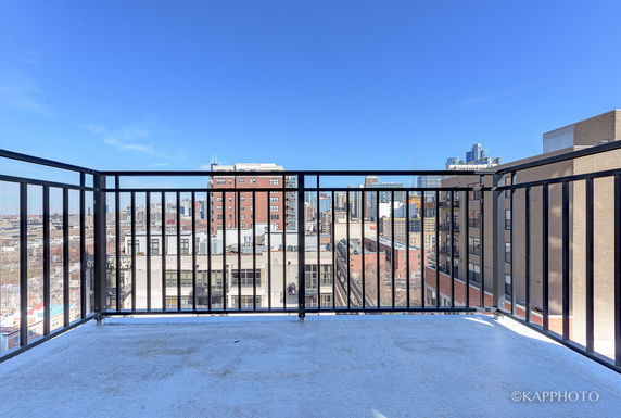 A balcony with a railing overlooking a cityscape with buildings in the background.