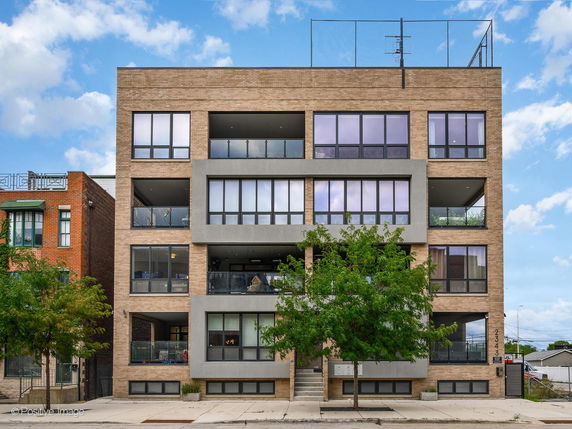 Front view of a multi-story brick apartment building with large windows and balconies.