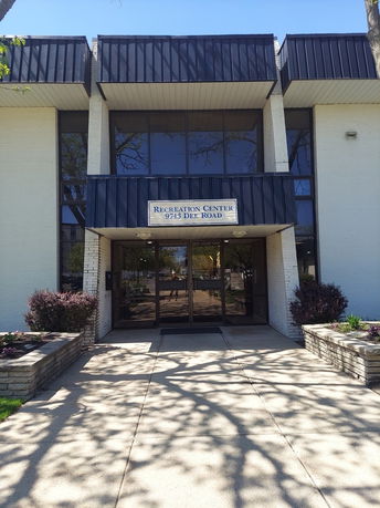 Front view of a recreation center building with large glass windows and brick entrance.