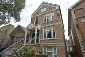 Front view of a three-story brick house with a pitched roof and multiple windows.