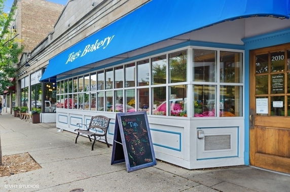 Front view of a bakery with a blue awning and large windows.