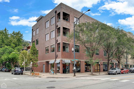 Front view of a multi-story brick building located at a street corner.
