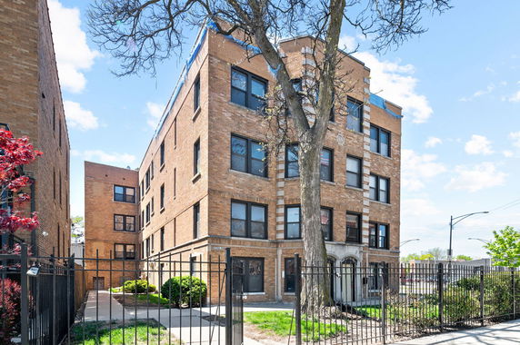 Front view of a multi-story brick building with a gated entrance.