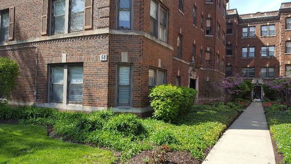 Front view of a multi-story brick apartment building with pathway.