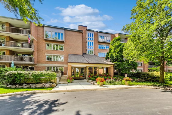 Front view of a multi-story building with balconies and a landscaped entrance.