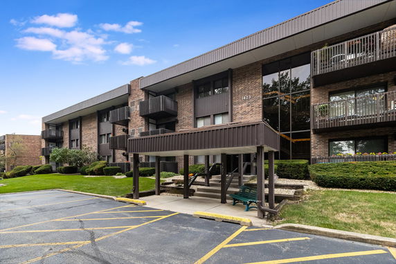 Front view of a multi-story apartment building with balconies and covered entrance.