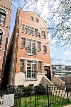 Front view of a multi-story brick building with large windows and small balconies.