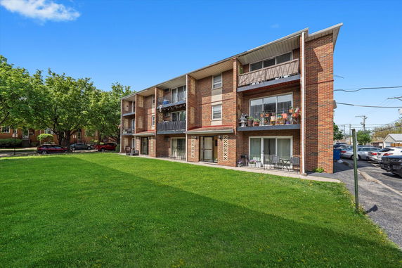 Front view of a three-story brick apartment building with balconies.