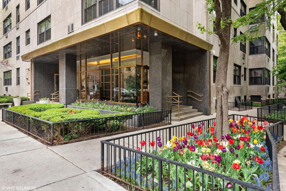 Front view of a building entrance with glass doors and surrounding planters.