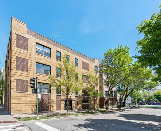 Front view of a four-story brick building on a street corner.