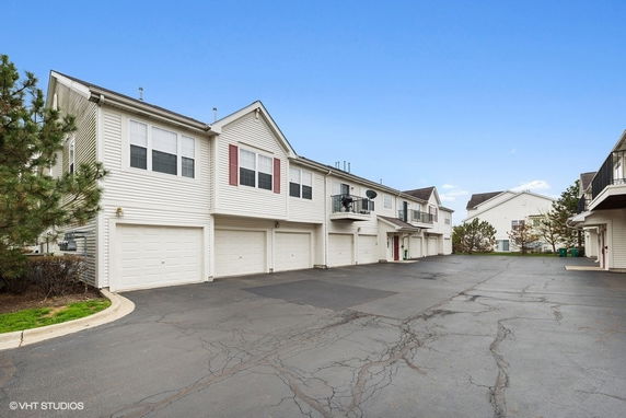Outdoor parking area in front of multi-unit residential buildings with garages.