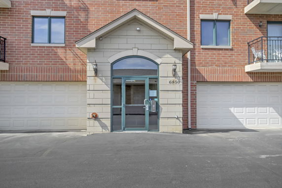 Front view of a building entrance with dual garages and brick facade.