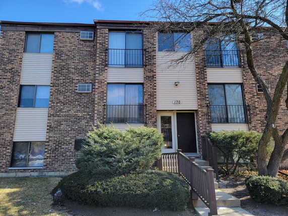 Front view of a multi-story brick apartment building with multiple windows and a central entrance.